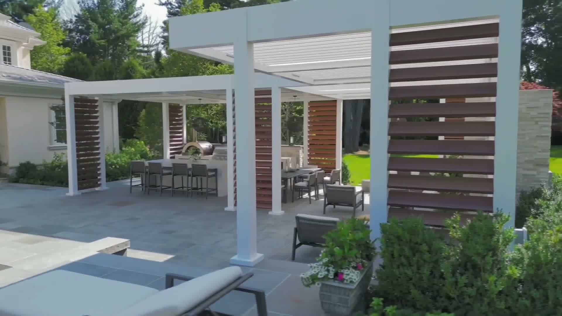 Completed pergola with wood privacy screens, outdoor kitchen, and loungers
