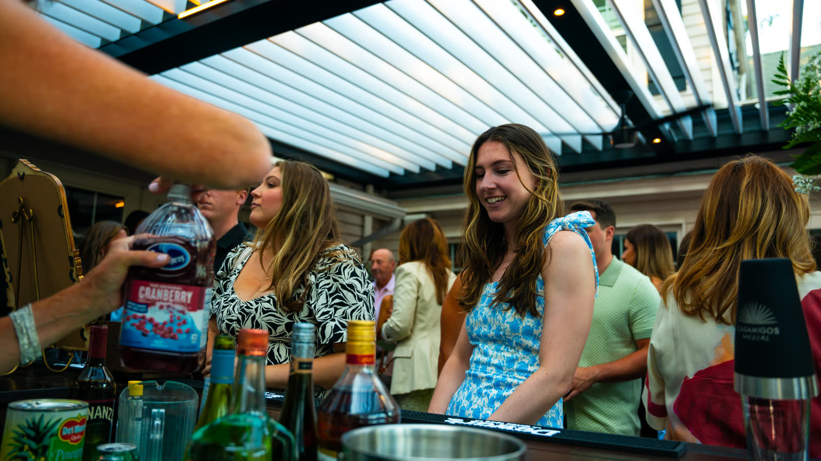 Guests at outdoor bar under louvered pergola