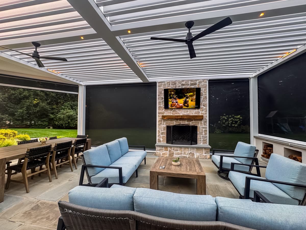 Fully enclosed pergola with fireplace, TV, motorized screens, and lounge seating