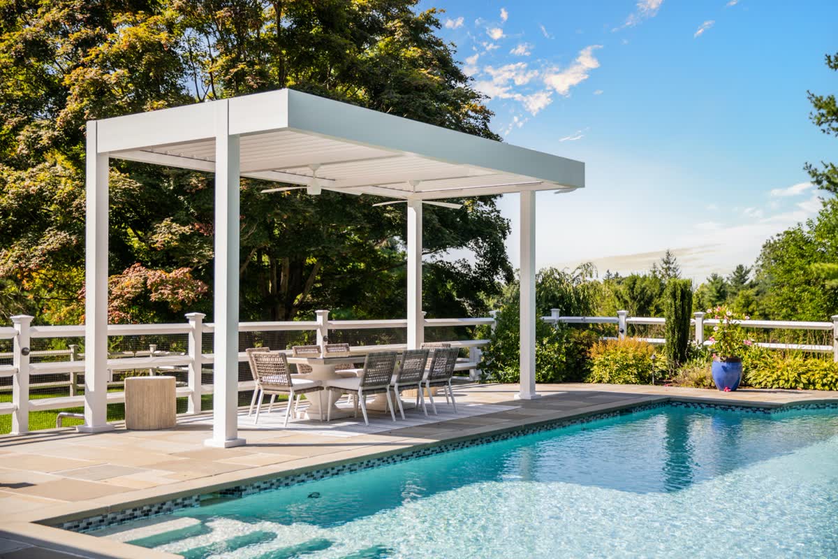 White modern louvered pergola poolside in daylight